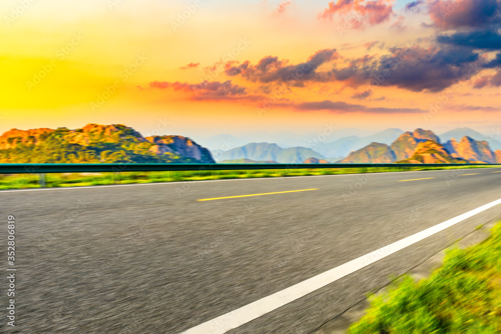 Motion blurred mountain road,asphalt roads and mountains with sky clouds at sunset.