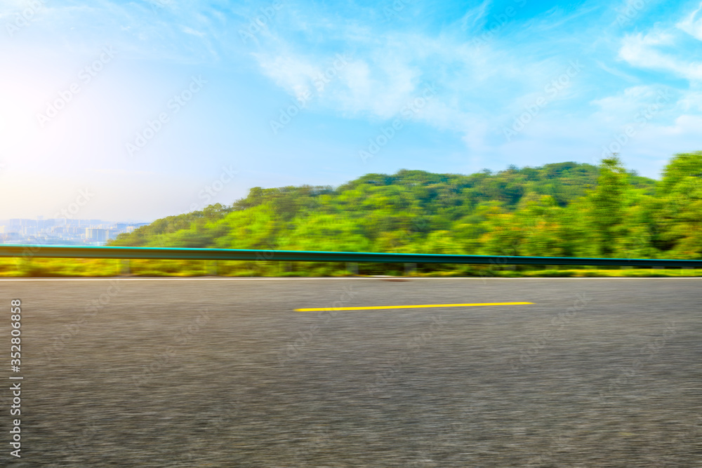 快速移动的沥青道路和绿色森林景观。