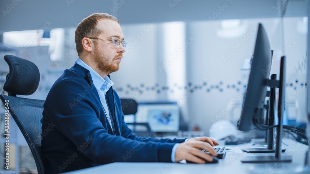 Shot of a Heavy Industry Engineer Working on Personal Computer in Modern Industrial Factory with Hig