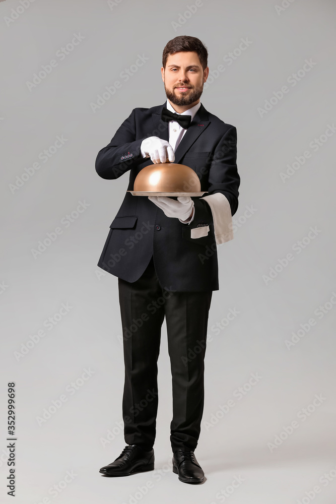 Handsome male waiter on grey background