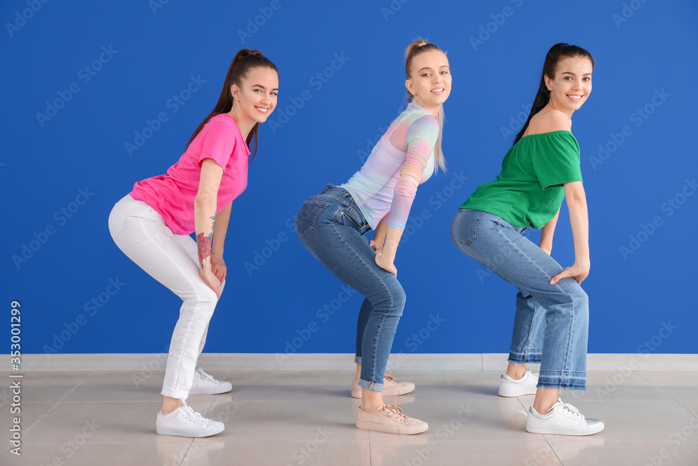 Beautiful young women dancing against color wall