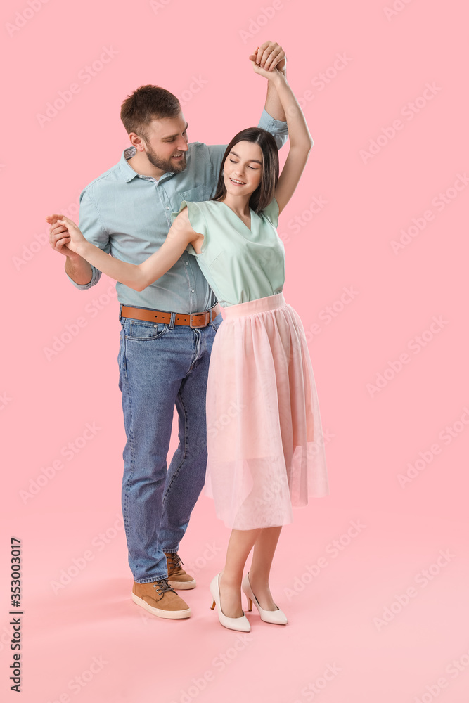 Happy young couple dancing against color background