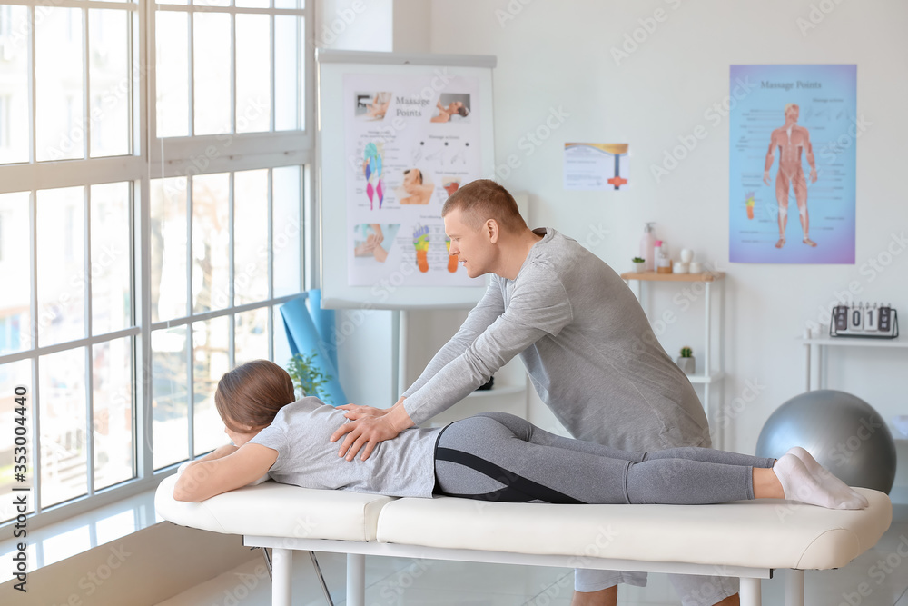 Massage therapist working with female patient in medical center