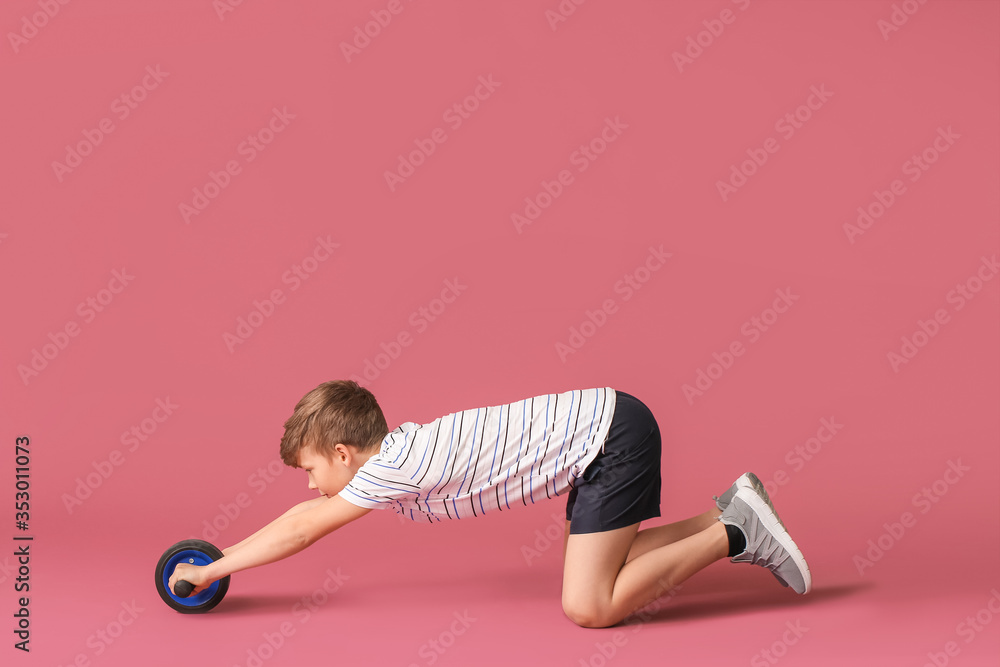 Sporty little boy training against color background