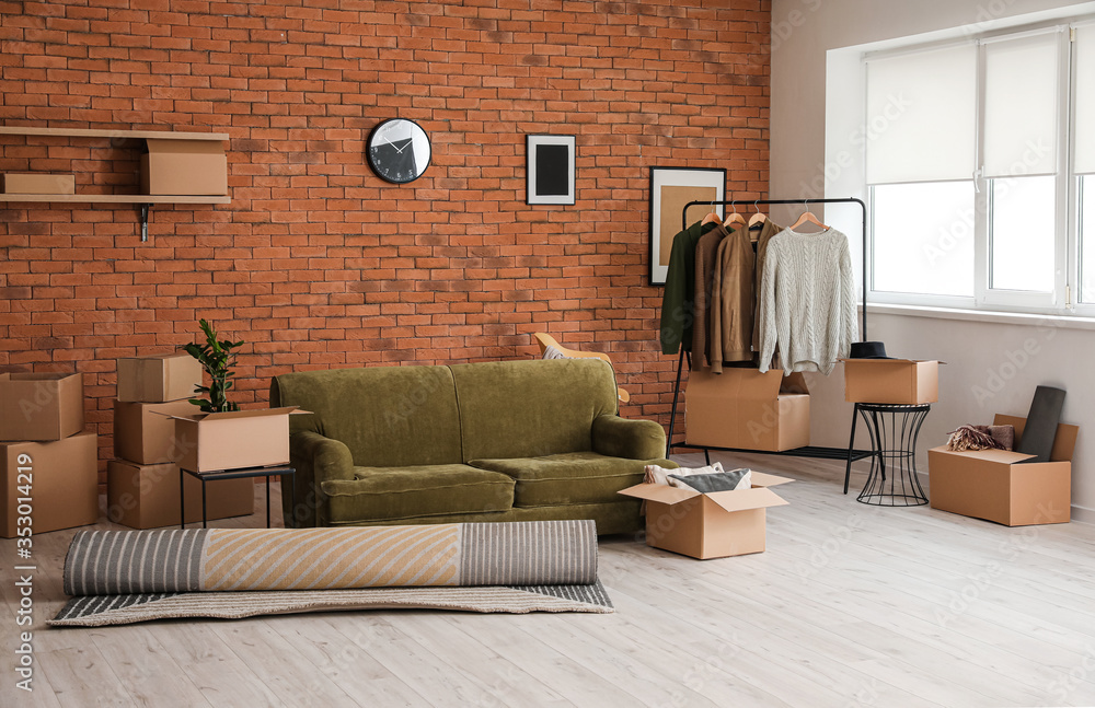 Cardboard boxes with belongings and sofa in new flat on moving day