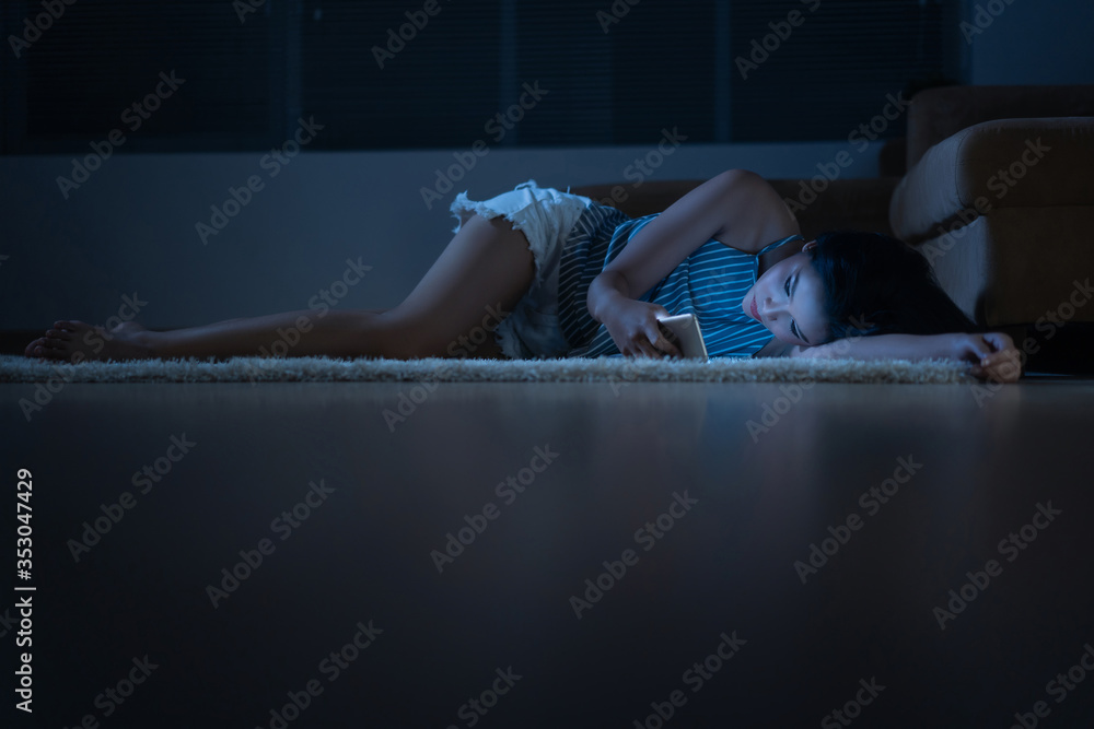 Asian woman uses her phone at night She sleeps on the floor