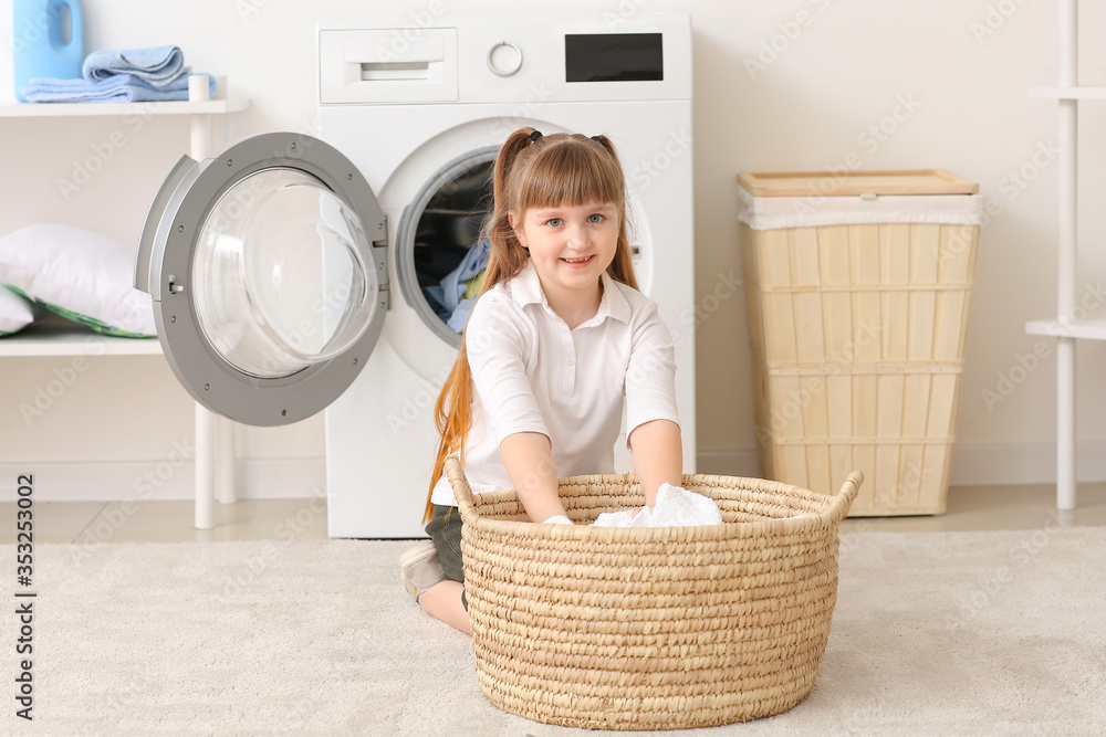 Cute little girl doing laundry at home