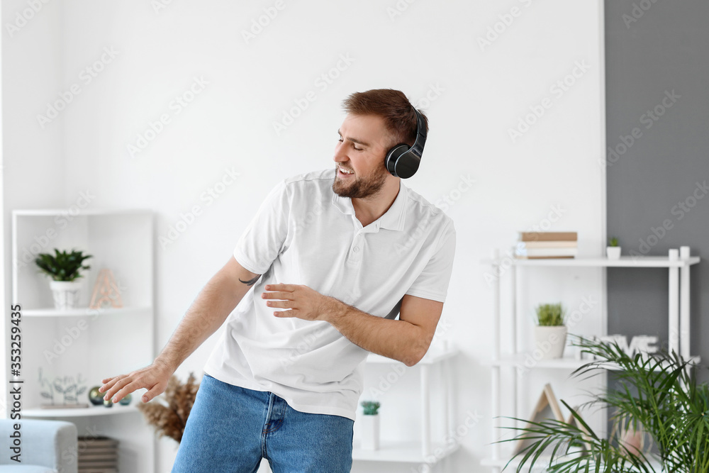 Handsome young man dancing and listening to music at home