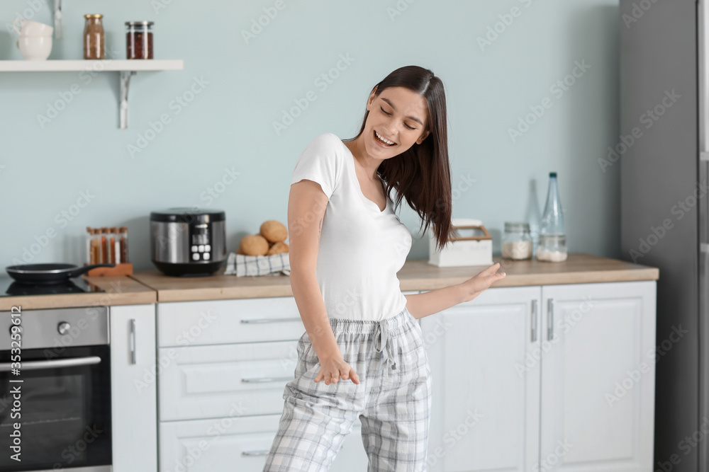 Beautiful young woman dancing in kitchen