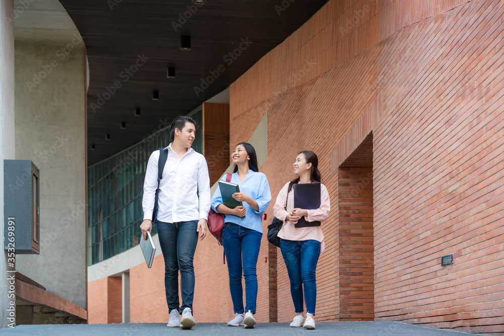 大学课间休息时，三名亚裔学生在大学礼堂一起散步和交谈。