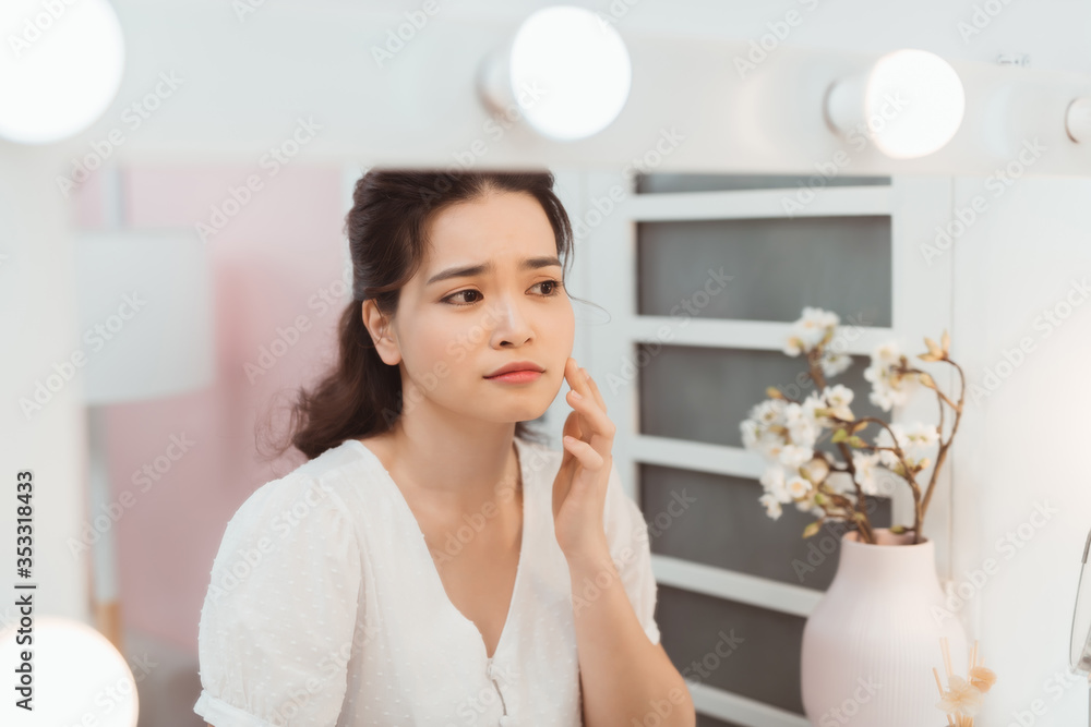 女人看起来很痛苦，因为痤疮问题摸了摸脸