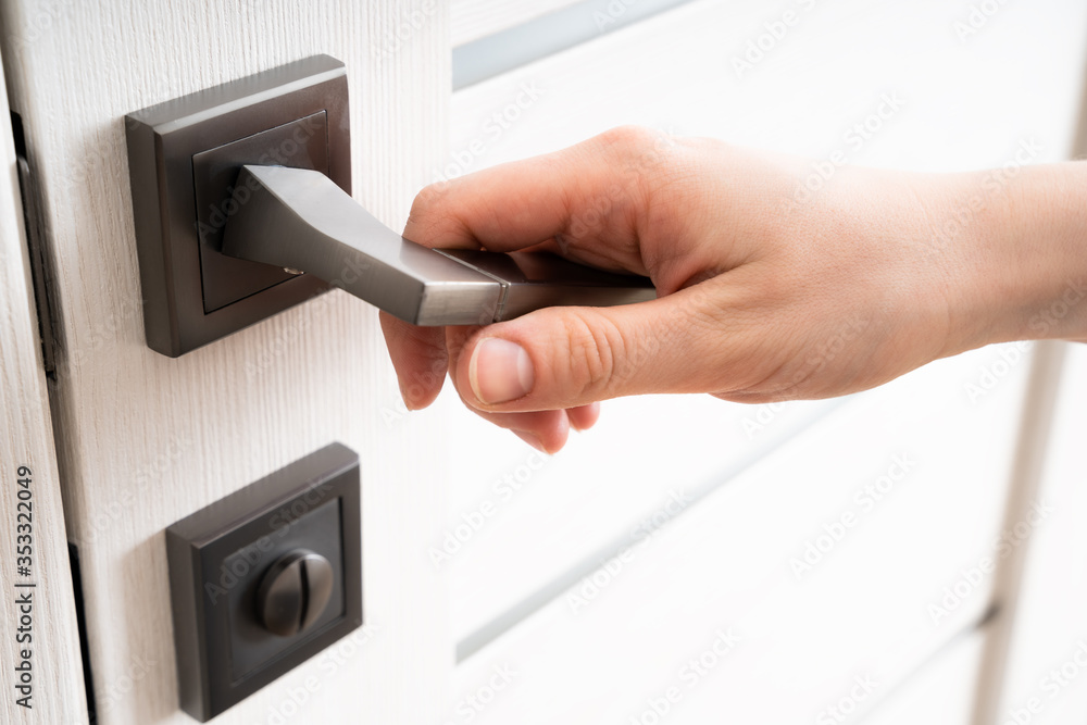 A woman opens a door handle with her hand