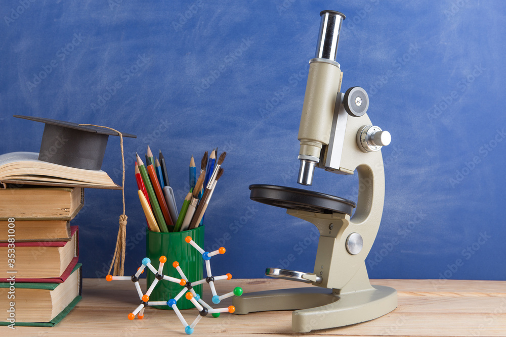 Education and sciences concept - books on the teacher desk in the auditorium, chalkboard on the back