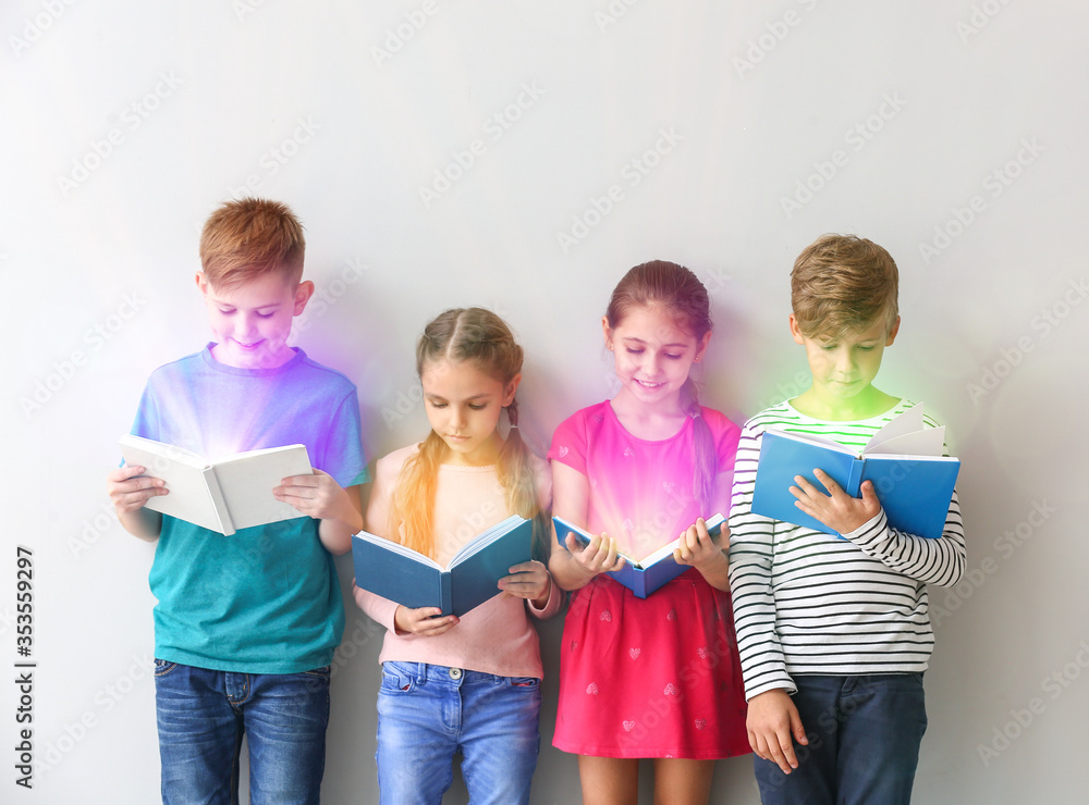 Cute little children reading books on grey background