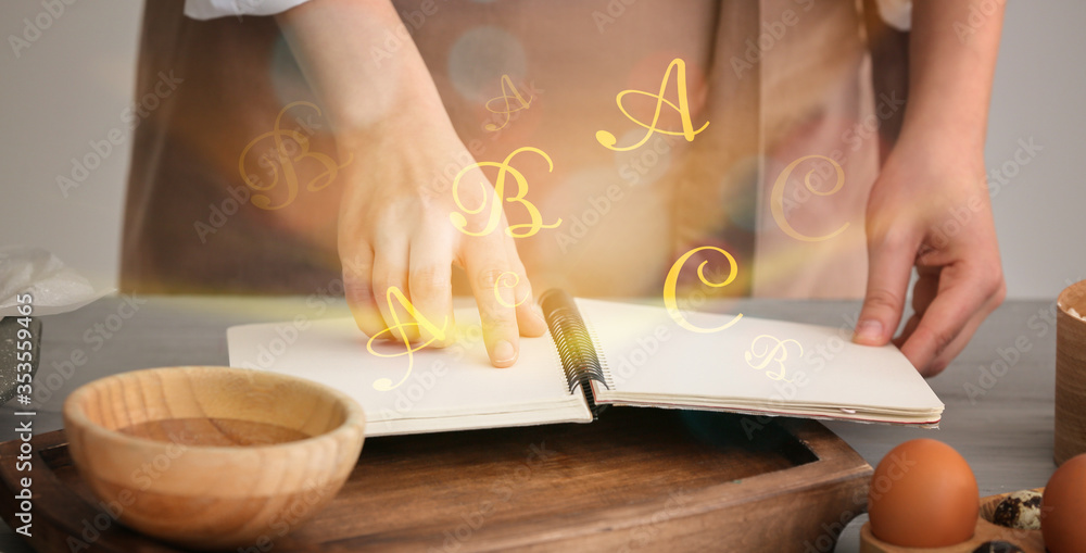 Woman with cook book preparing food in kitchen