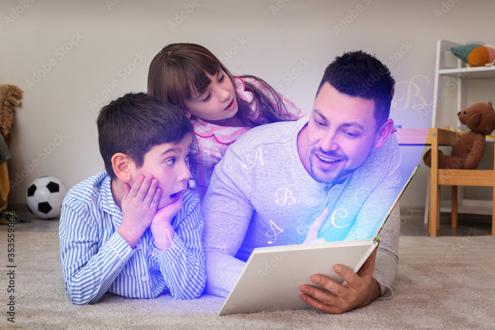 Father and his little children reading bedtime story at home