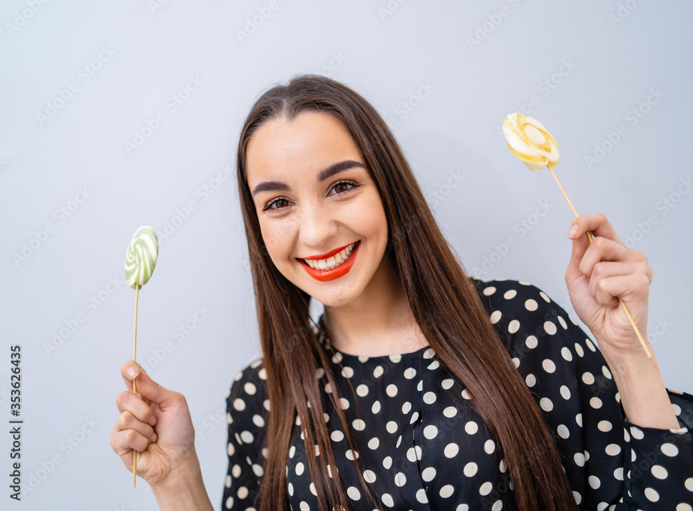 女孩手里拿着两个棒棒糖。白色背景下拿着糖果的快乐女士。