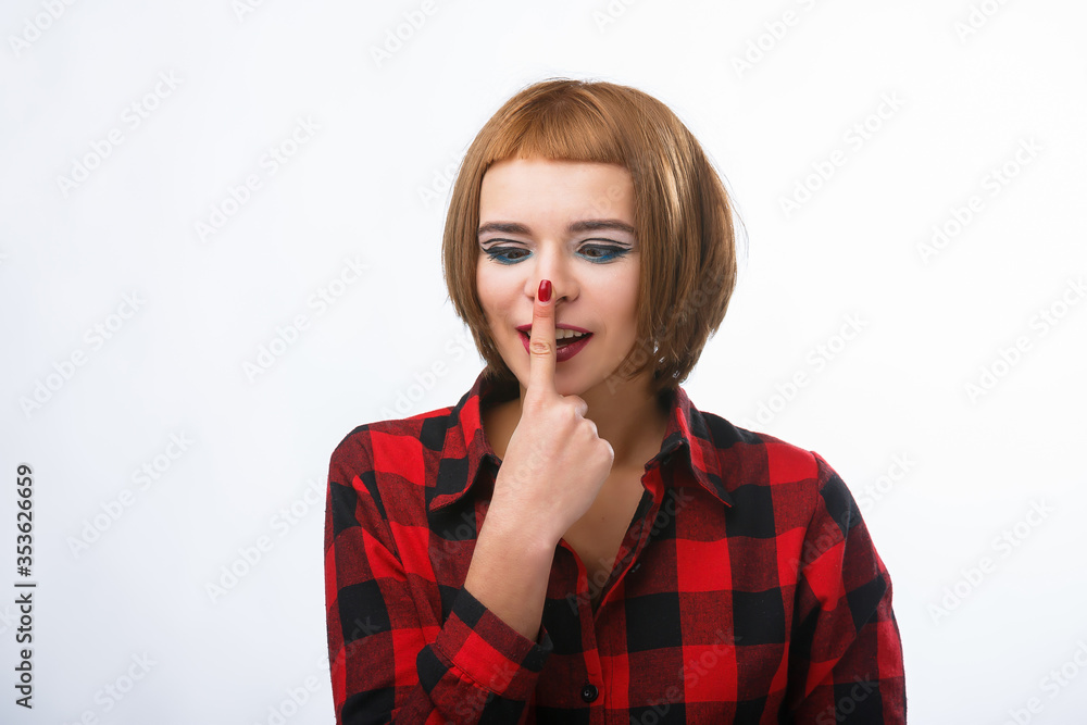 Young casual style woman portrait isolated over white background. Girl touches nose with finger. Red