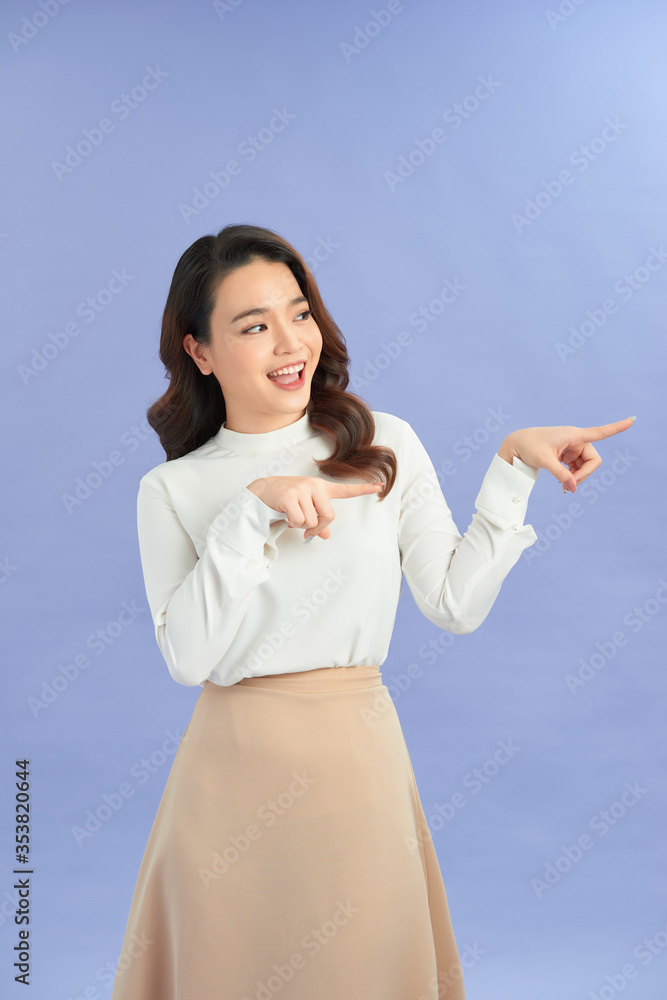 Attractive brunette girl isolated over purple background pointing at a copy space