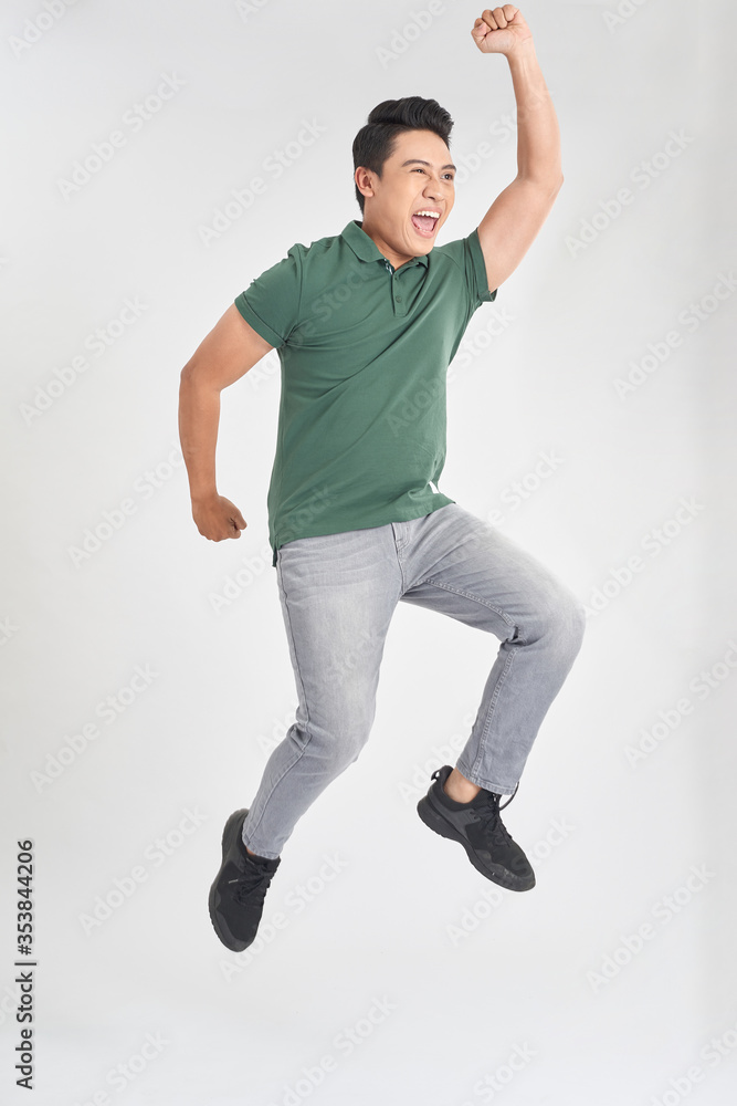 Happy excited cheerful young man jumping and celebrating success isolated on a white background