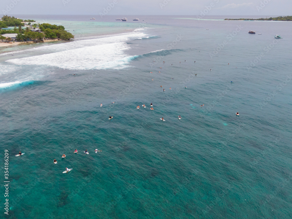 AERIAL: Active tourists gather in the ocean at the line up to surf some waves.