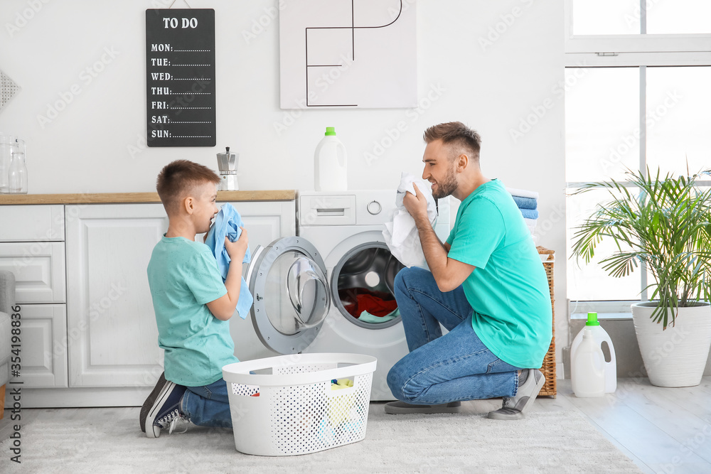 Man and his little son doing laundry at home