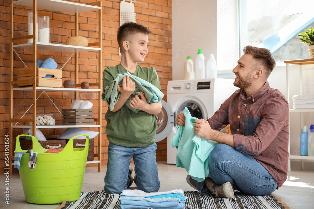 Man and his little son doing laundry at home