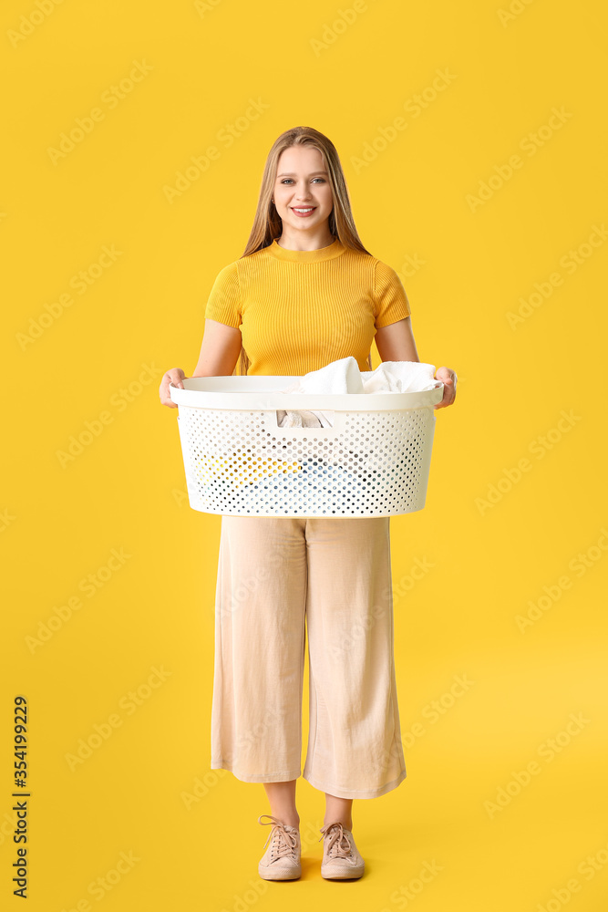 Young woman with laundry on color background