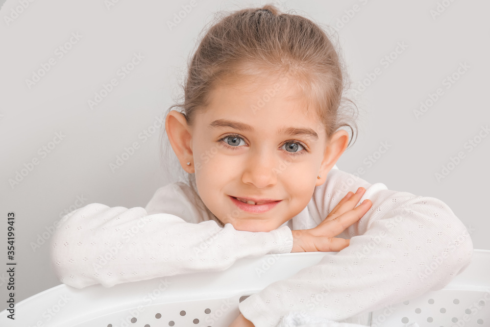 Little girl with laundry on grey background