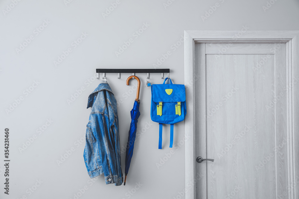 Umbrella with clothes and school backpack hanging on wall in hall