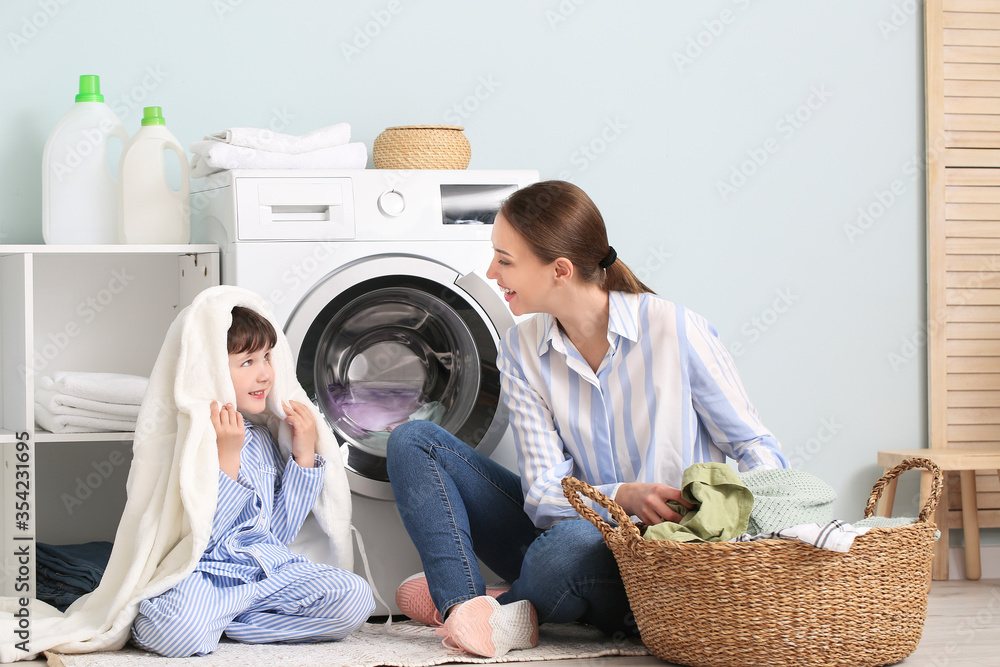 Young woman with her little son doing laundry at home