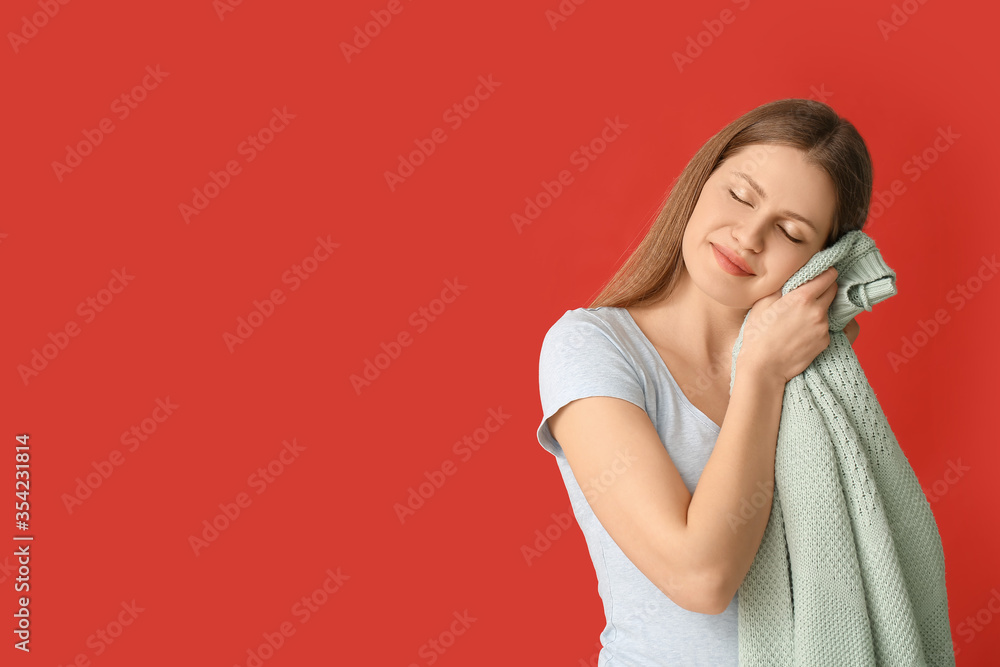 Young woman with clean laundry on color background