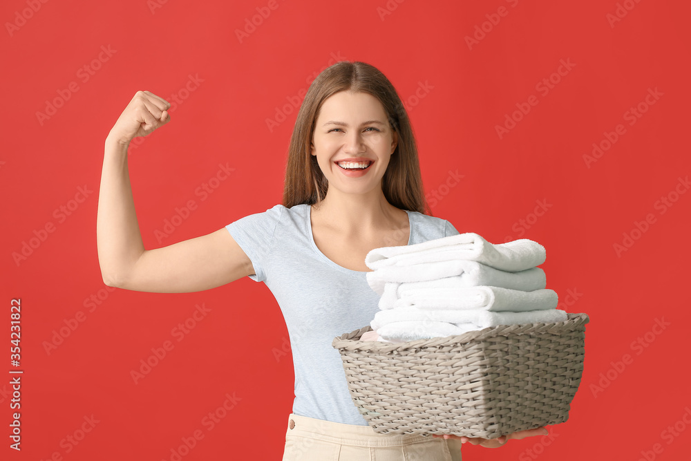 Young woman with clean laundry on color background