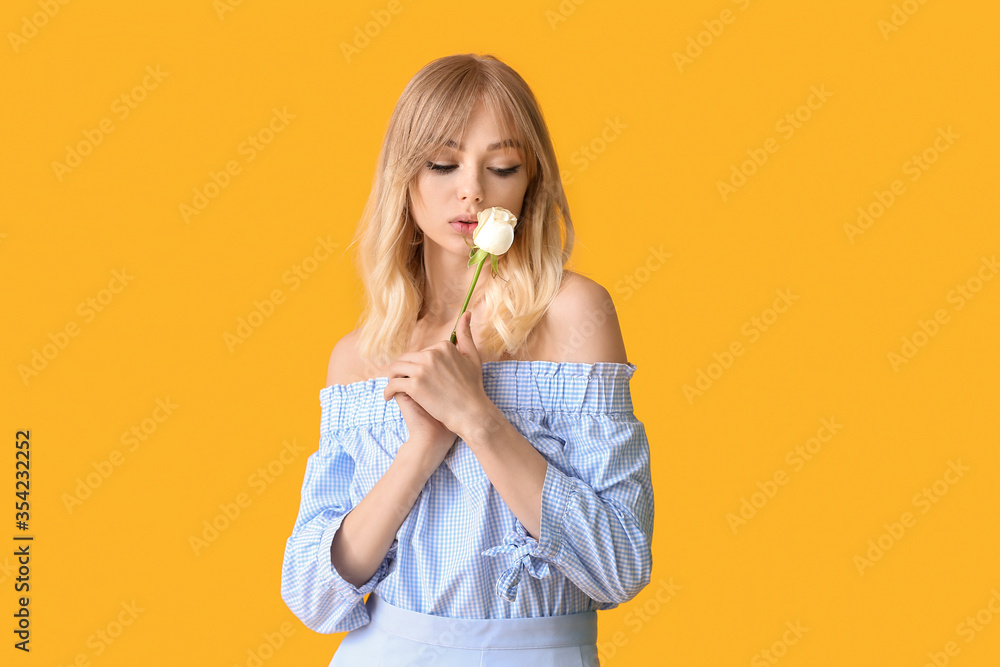 Beautiful young woman with rose on color background