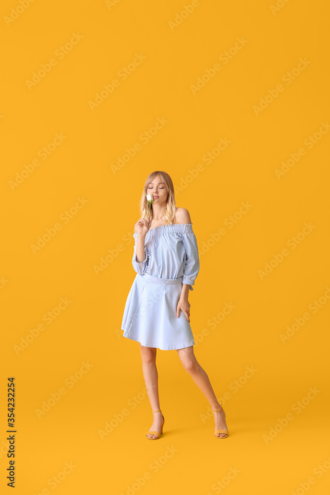 Beautiful young woman with rose on color background