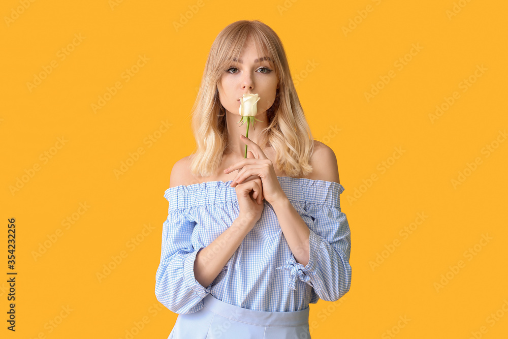 Beautiful young woman with rose on color background