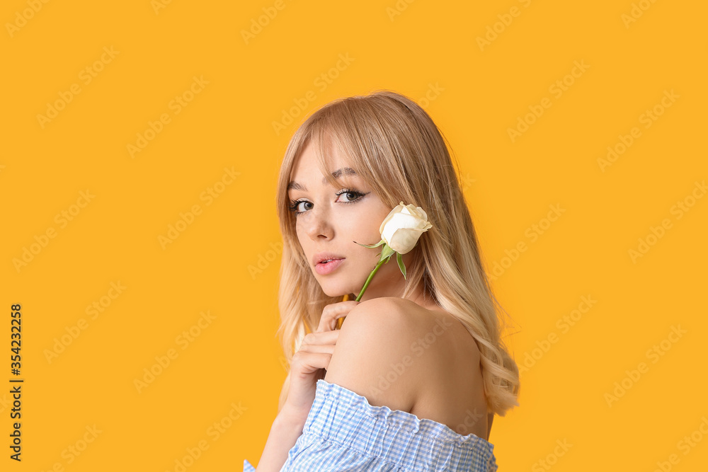 Beautiful young woman with rose on color background