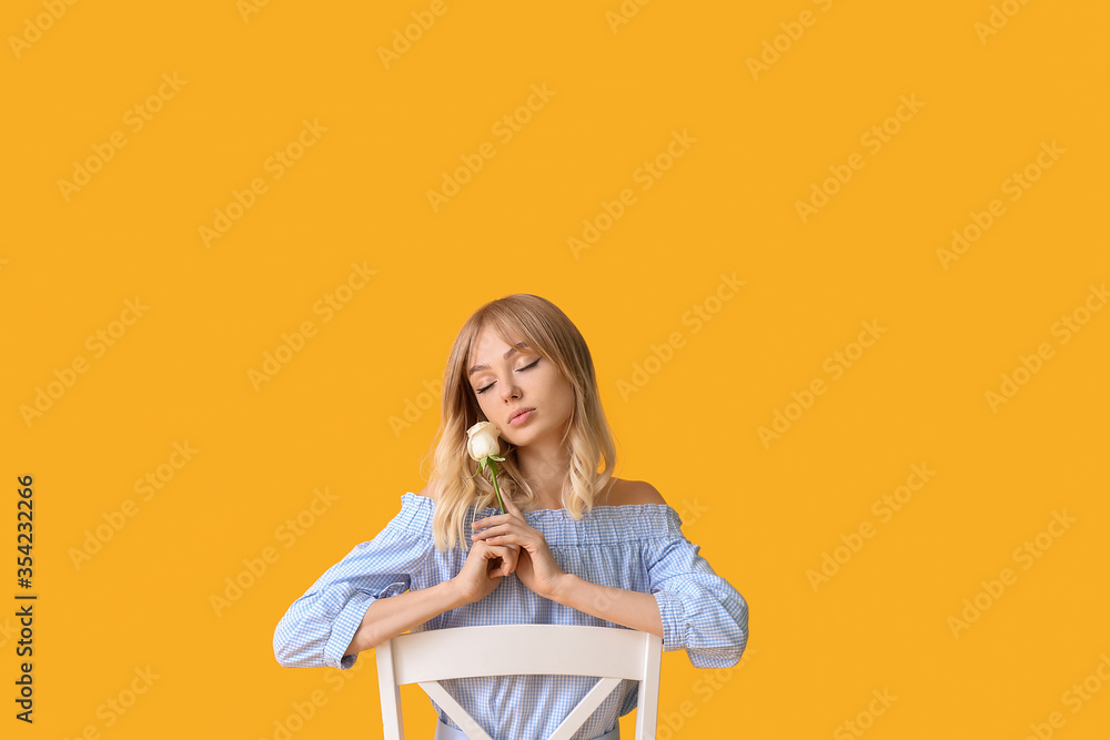 Beautiful young woman with rose on color background