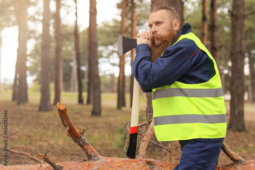 Handsome lumberjack with axe in forest