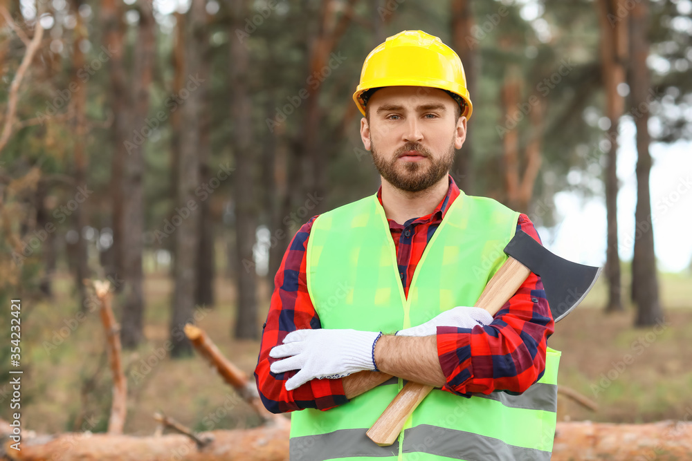 Handsome lumberjack with axe in forest