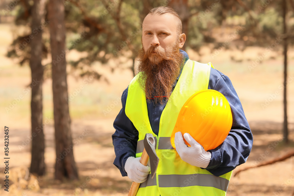 Handsome lumberjack with axe in forest