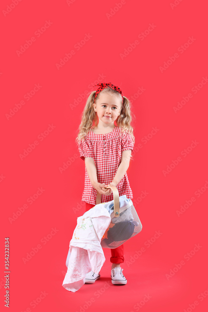 Cute little girl with dirty laundry on color background