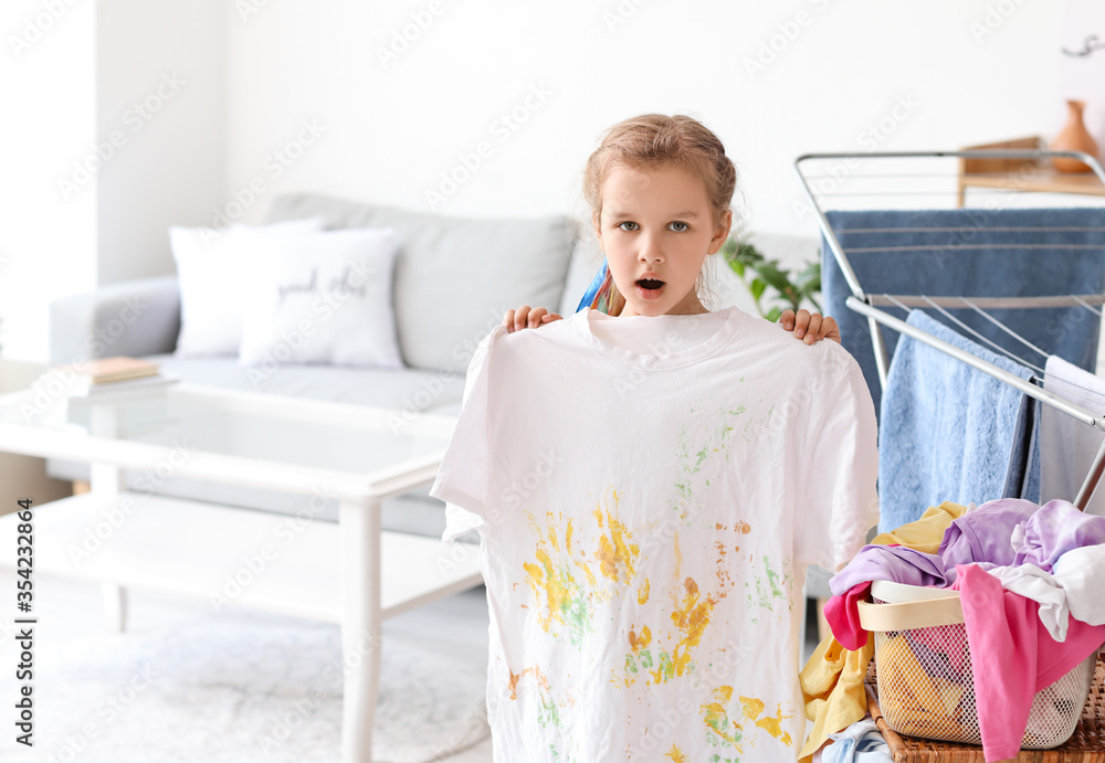 Little girl with dirty laundry at home