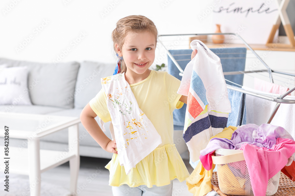 Little girl with dirty laundry at home