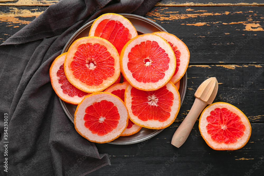 Plate with fresh cut grapefruit on dark wooden background