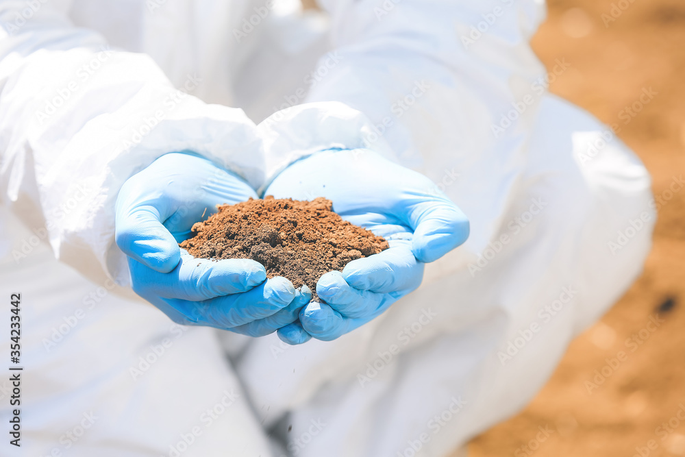 Scientist with sample of soil in field, closeup