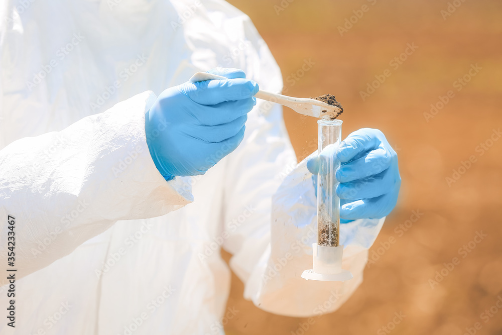 Scientist studying samples of soil in field, closeup