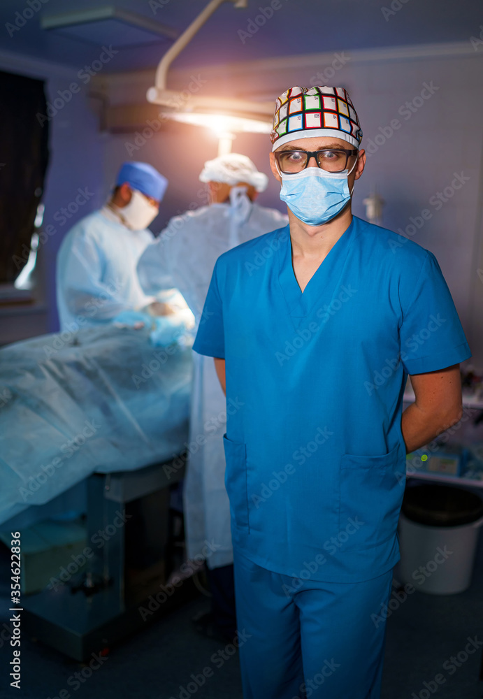 Portrait of young surgical doctor in scrubs standing in operating theatre. Portrait of male doctor i