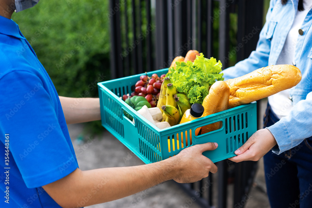 Asian delivery man blue uniform wearing medical face mask making grocery service giving fresh food t