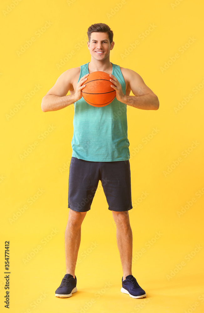 Sporty young man with ball on color background